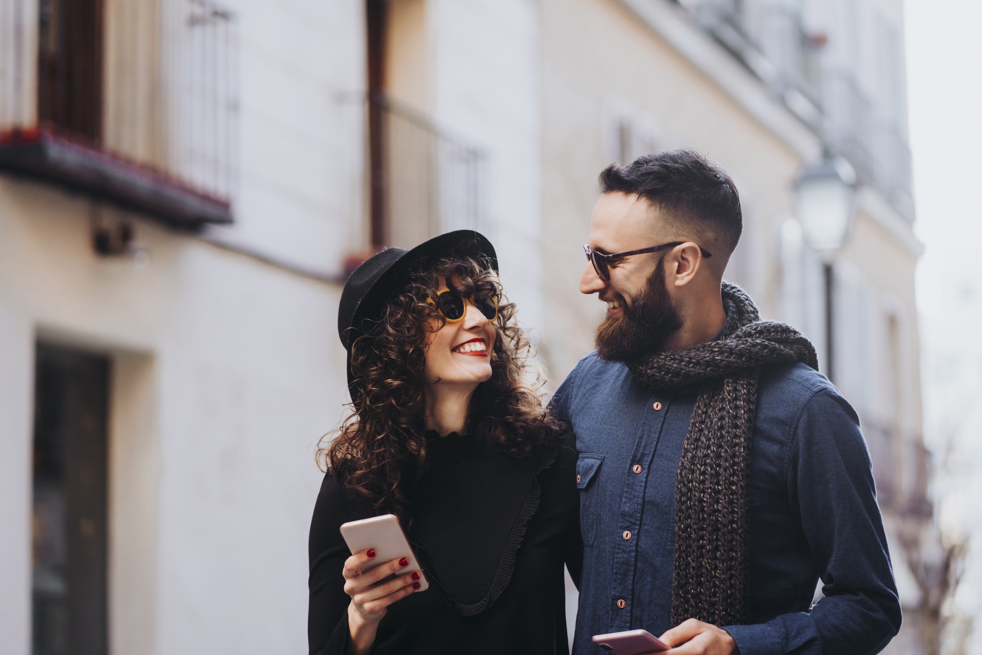 Two happy friends using the mobile in the street. Friendship concept.